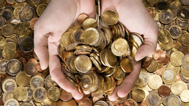 Zwei Hände halten eine große Menge an Euro-Münzen.