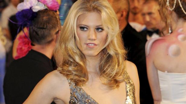 Eine blonde Frau in einem glitzernden Kleid auf einer Veranstaltung.