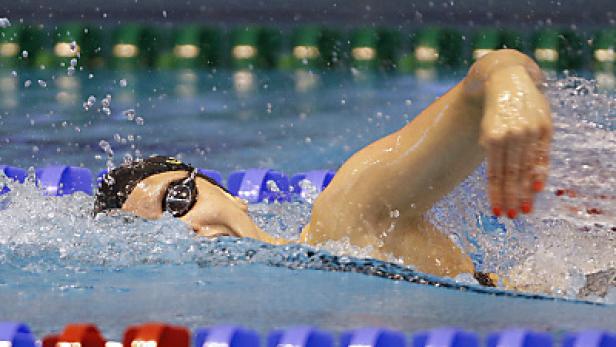 Eine Schwimmerin mit Schwimmbrille zieht ihre Bahn im Schwimmbecken.