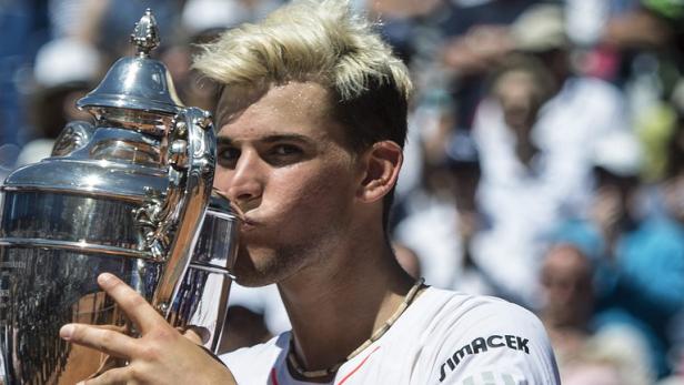 Ein Tennisspieler küsst eine silberne Trophäe vor einer Zuschauermenge.