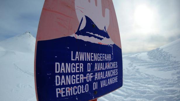 Ein Schild warnt vor Lawinengefahr in einem verschneiten Gebiet.