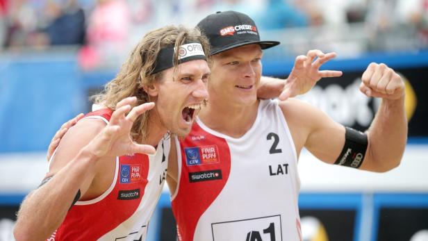 Zwei Beachvolleyballspieler aus Lettland feiern einen Sieg.
