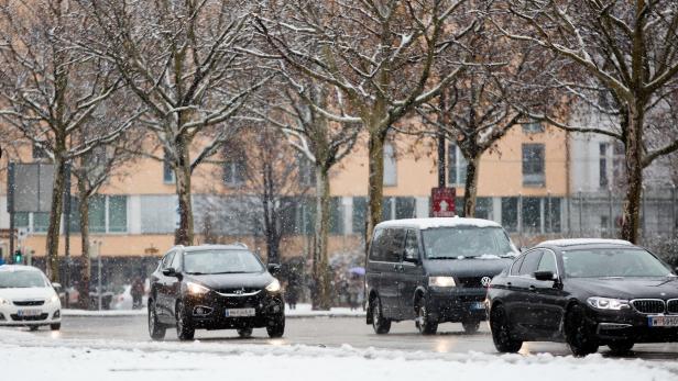 Autos fahren auf einer verschneiten Straße in der Stadt.