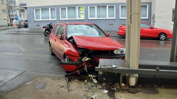 Ein roter PKW mit schweren Schäden an der Front nach einem Unfall.