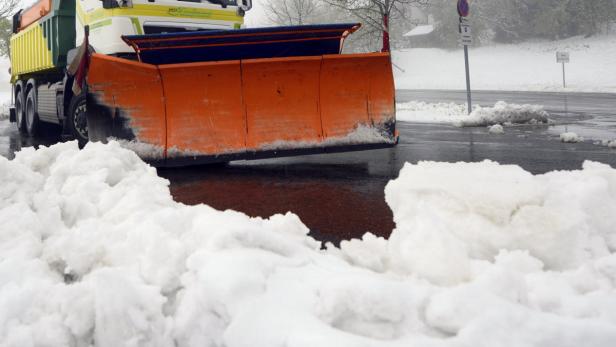 Ein Schneepflug räumt eine Straße von Schnee frei.