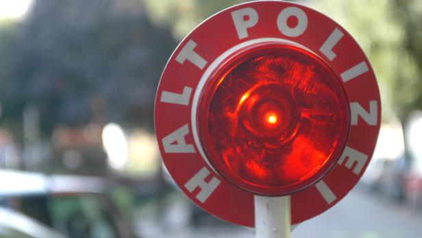 Ein rotes „Halt Polizei“-Schild mit eingeschaltetem Licht.