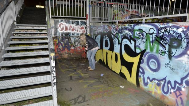 Eine Frau steht in einer Unterführung mit Graffiti an den Wänden.