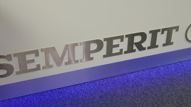 Das Semperit-Logo an einer Wand mit blauem Teppichboden.