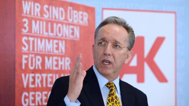 Ein Mann mit Brille gestikuliert vor einem Banner mit der Aufschrift „Wir sind über 3 Millionen Stimmen“.