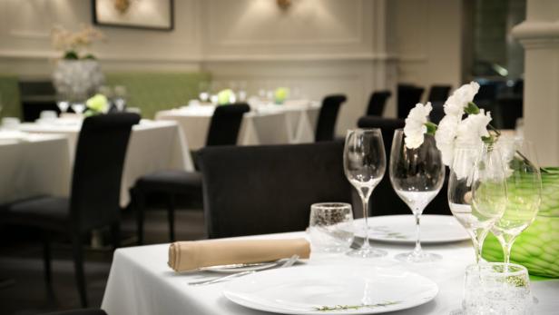 Ein gedeckter Tisch in einem eleganten Restaurant mit weißen Blumen und Weingläsern.