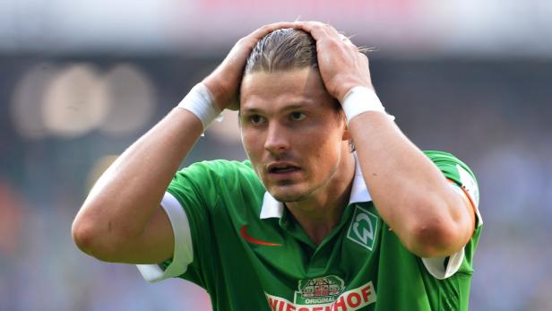 Ein Fußballspieler in Grün mit den Händen am Kopf wirkt frustriert.