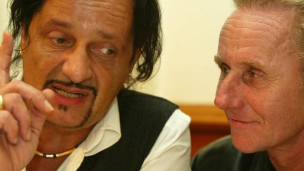 Zwei Männer im Gespräch, einer gestikuliert mit erhobenem Zeigefinger.