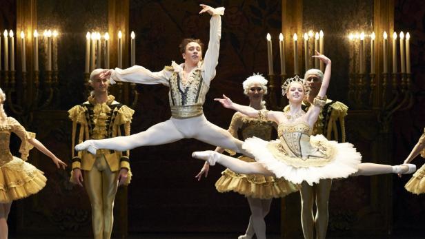 Eine Gruppe von Balletttänzern in historischen Kostümen führt eine Szene auf einer Bühne auf.