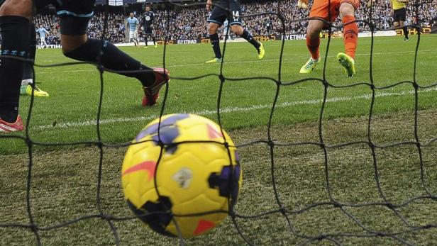 Ein gelb-blauer Fußball liegt im Netz eines Fußballtors.