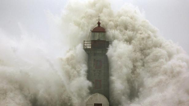 Ein Leuchtturm wird von einer riesigen Welle umspült.