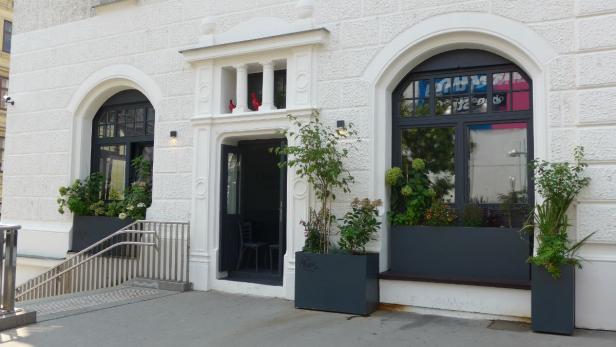 Die Fassade eines Gebäudes mit Eingangstür und bepflanzten Fenstern.