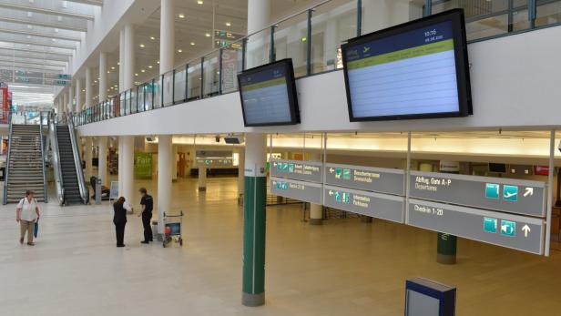 Flughafen mit Anzeigetafeln, Wegweisern und wartenden Personen.