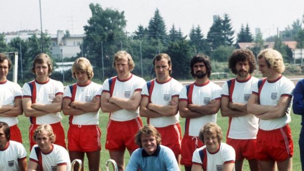 Eine Fußballmannschaft posiert für ein Gruppenfoto auf einem Rasenplatz.