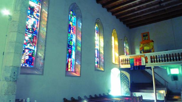 Die Sonnenstrahlen, durch die Glasfenster verfärbt, erleuchten das Kircheninnere