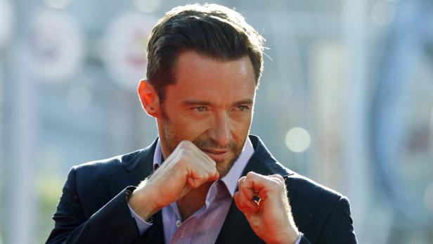 Hugh Jackman posiert mit geballten Fäusten für ein Foto.