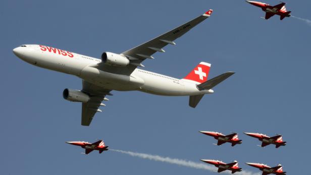 Passagiermaschine der Swiss (Airbus 330), begleitet von Jets der Schweizer Luftwaffe, bei einer Flugshow im September 2014.