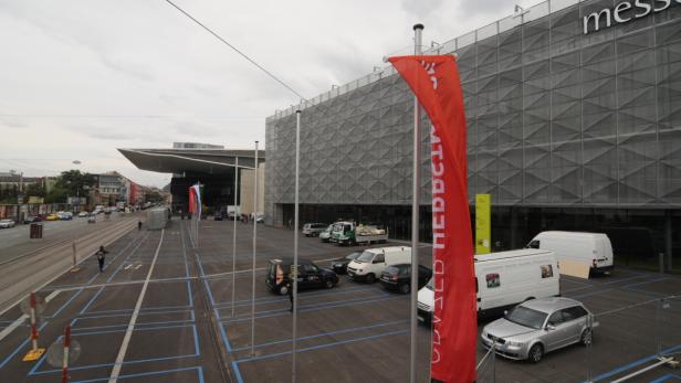 Das Messezentrum mit Parkplatz und roter Werbefahne im Vordergrund.