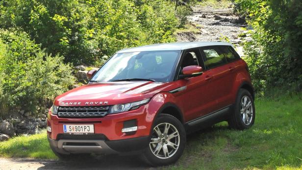 Ein roter Range Rover Evoque steht auf einer Wiese.