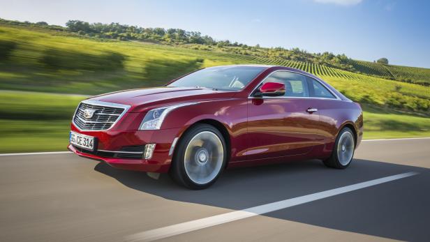 Ein roter Cadillac ATS fährt auf einer Landstraße an einem Weinberg vorbei.