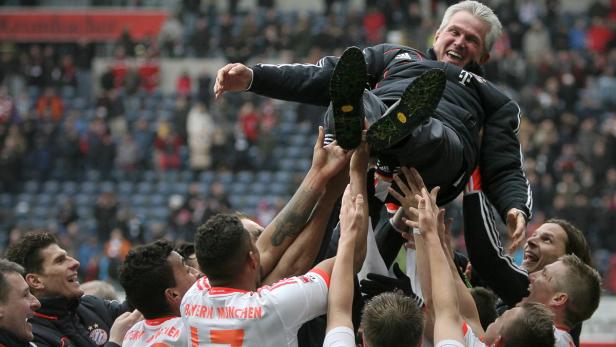 Fußballspieler des FC Bayern München werfen ihren Trainer in die Luft.