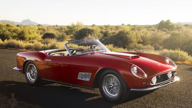 Ein roter Ferrari 250 GT California Spider steht auf einer asphaltierten Straße.