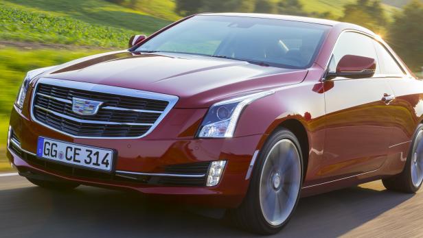 Ein roter Cadillac fährt auf einer Landstraße.