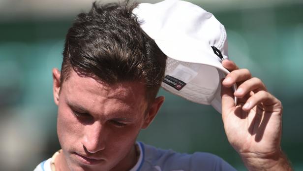 Ein Mann hält eine weiße Tenniskappe in der Hand.