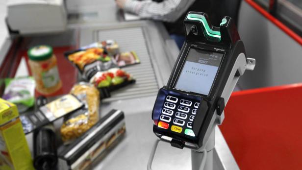 Ein Kassensystem zeigt „Vorgang erfolgreich“ an, während Lebensmittel auf dem Kassenband liegen.