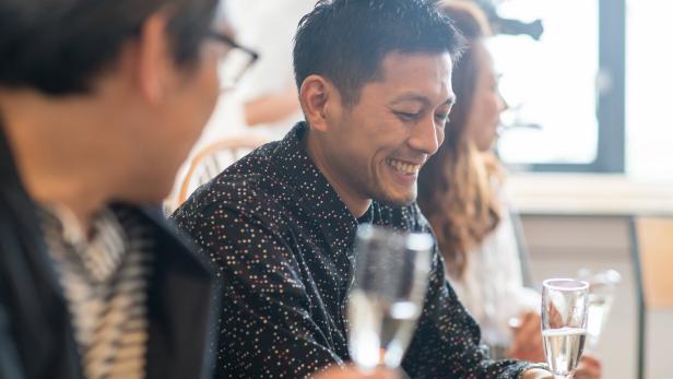 Ein lächelnder Mann hält ein Glas Sekt in der Hand.