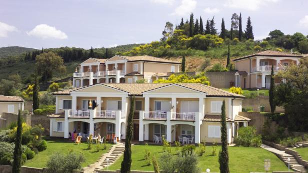 Mehrere Ferienwohnungen mit Balkonen auf einem grünen Hügel.