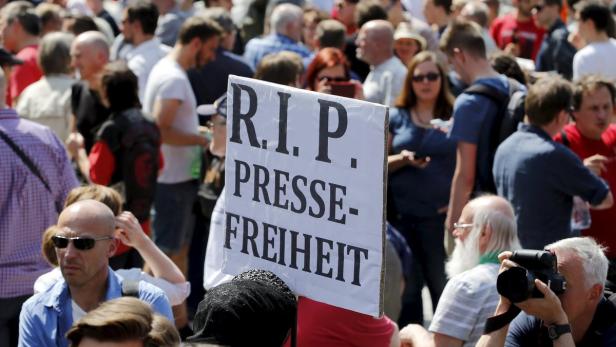 Eine Menschenmenge demonstriert mit einem Schild „R.I.P. Pressefreiheit“.