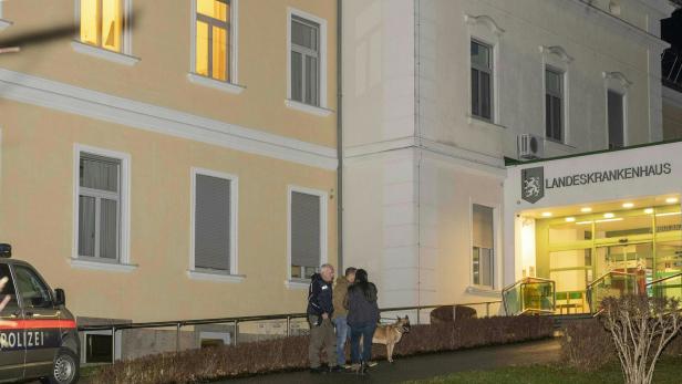 Polizisten mit einem Spürhund stehen vor dem Landeskrankenhaus.