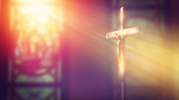 crucifix, jesus on the cross in church with ray of light from stained glass