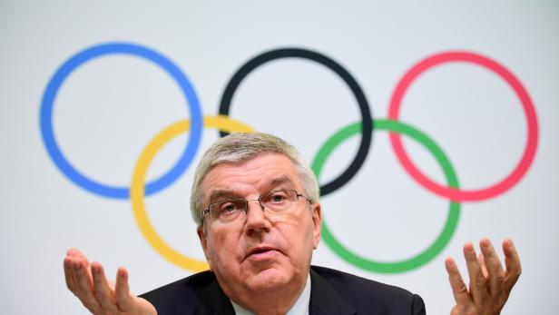 Thomas Bach, Präsident des IOC, gestikuliert vor dem Hintergrund der Olympischen Ringe.