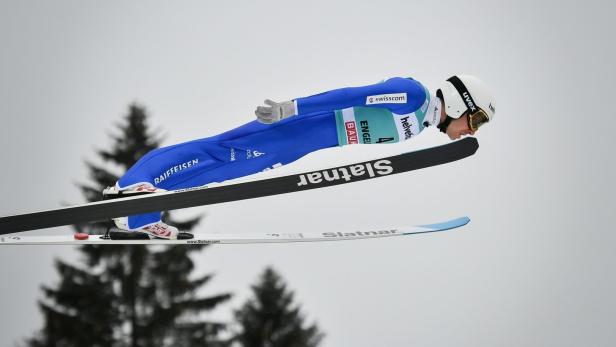 Ein Skispringer in blauem Anzug während eines Sprungs.