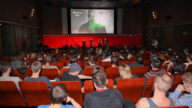 Zuschauer sitzen in einem Kinosaal vor der Leinwand, auf der „Breaking Bad“ läuft.