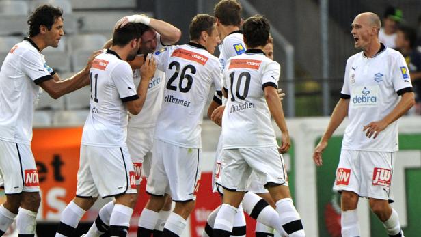Eine Gruppe Fußballspieler in weißen Trikots feiert ein Tor.