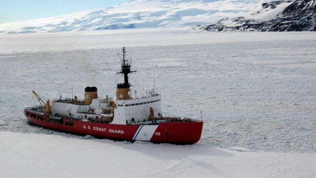 Ein rot-weißer Eisbrecher der US-Küstenwache fährt durch eine eisige Landschaft.