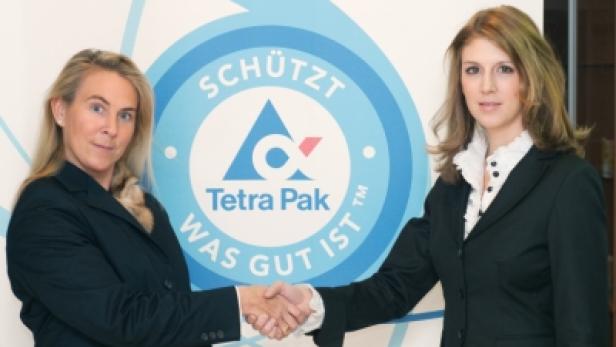 Zwei Frauen schütteln sich vor einem Tetra Pak-Logo die Hände.