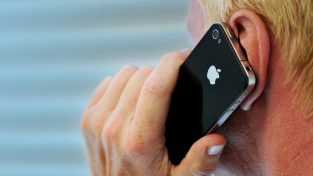 Eine Person telefoniert mit einem schwarzen iPhone.