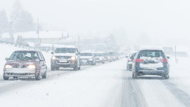 Autos fahren bei starkem Schneefall auf einer Straße in der Nähe von Heissnitz und Haus.