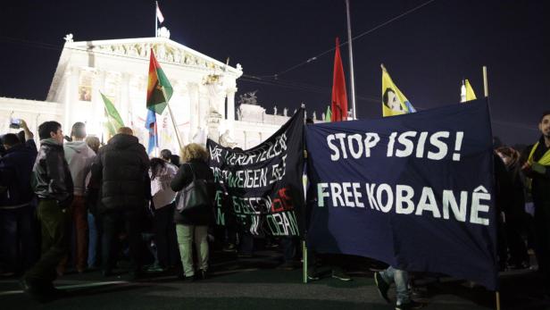Eine Demonstration mit Bannern gegen ISIS und für Kobanê vor einem Gebäude.
