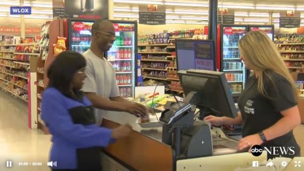 Ein Paar wird an einer Kasse in einem Wayne Lee's Supermarkt bedient.