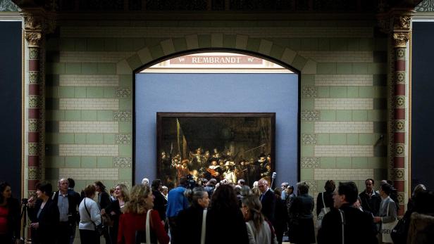 Besucher betrachten Rembrandts „Die Nachtwache“ in einem Museum.