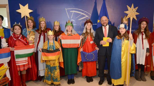 Eine Gruppe Sternsinger mit Flaggen verschiedener Länder und Martin Schulz im Europäischen Parlament.